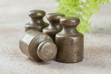 Obraz na płótnie Canvas Four antique bronze weights for scales on concrete background.