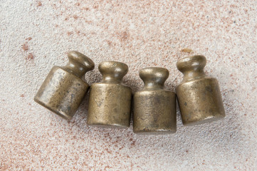 Four antique bronze weights for scales on concrete background.