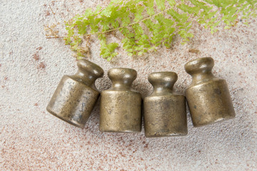 Four antique bronze weights for scales on concrete background.