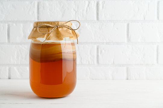 Homemade fermented kombucha tea in a glass jar on a background of a white brick wall. copy space