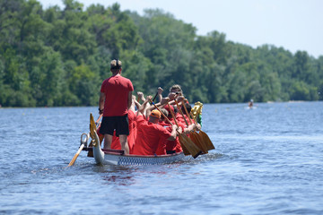 Oarsmen rowing a dragon boat on the river © Yurii Zushchyk
