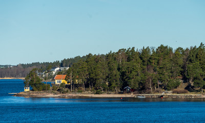 Picturesque summer houses painted in traditional falun red on dwellings island of the Stockholm archipelago in the Baltic Sea in the early morning.