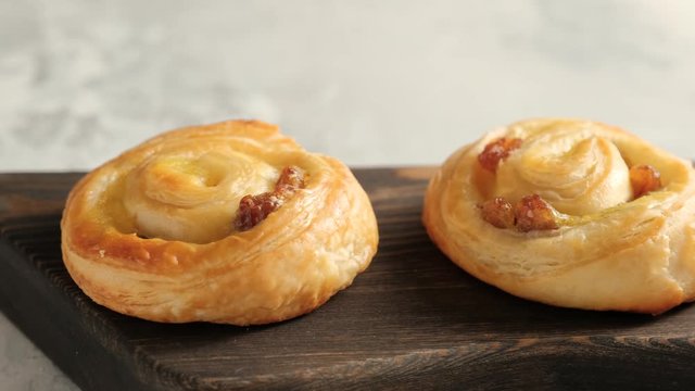 Fresh pastry sweet swirl buns with raisins on wooden board for breakfast or brunch. Party food concept. Camera slide right