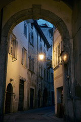 Italian cityscape evening mysterious narrow empty street by night. Night view of the Rovereto city