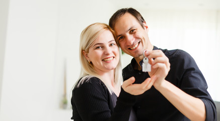 Happy smiling young couple showing a pair of keys of their new house