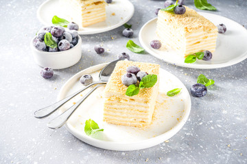 Homemade baked cake Napoleon, Millefeuille. Delicate custard cake garnished with berries and mint. On a gray concrete stone background.