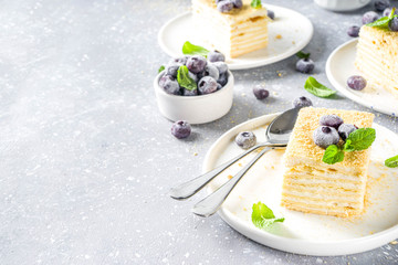 Homemade baked cake Napoleon, Millefeuille. Delicate custard cake garnished with berries and mint. On a gray concrete stone background.