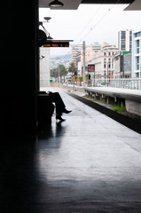 Young woman waiting at the train station. Silhouette of a passenger at the railway station, in the background of the city of Valparaiso, Chile. Stock photo with Vertical Screen Orientation