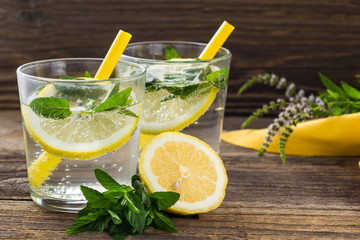 Lemonade or mojito cocktail with lemon and mint with ice. Cold summer refreshing drink decorated with yellow napkin
