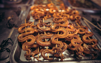 roasted snakes on display at an Asian market in Cambodia at night