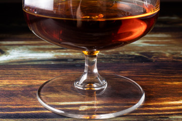 The leg of the glass for cognac. Dear elite alcohol on a dark brown background. Dishes for alcoholic beverages.