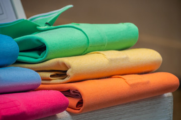 A pile of cotton polo shirts in many different colors, exposed in a shop window