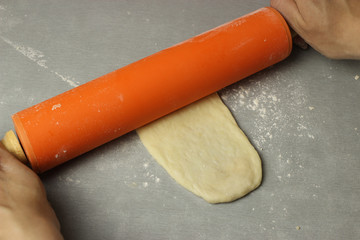 The dough is rolled out with a rolling pin on the table