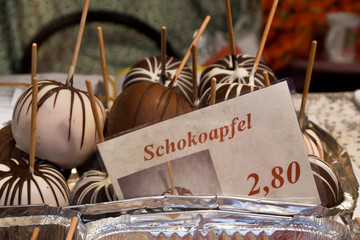 Sweet glazed red toffee candy apples on sticks for sale on farmer market or country fair.