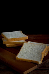 Homemade bread slides on a wooden chopping board in the kitchen at home on a black background and copy space. High carbohydrate food concept.