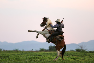 cowboy riding horse against sunset