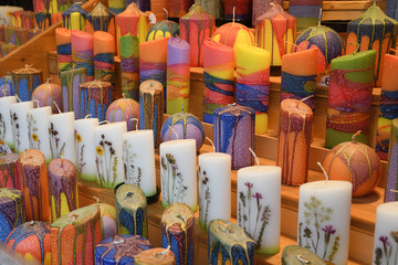 Obraz premium Many multicolored colorful red orange yellow paraffin stick candles arranged on shelves