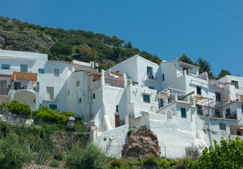 Fototapeta na wymiar White, traditional village houses on a steep hillside at the pretty Spanish village of Frigiliana. Buildings show their Moorish roots. The settlement is a quiet destination on the Costa del Sol.