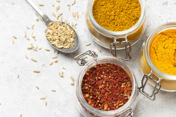 Spices and condiments in glass jars on a light gray table. Spices close-up with space for text. The view from the top