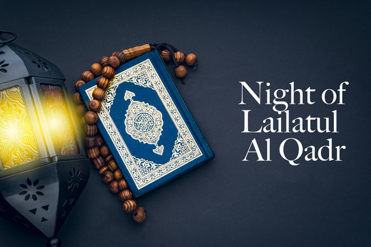 LAILATUL QADR text with Holy Al Quran with written arabic calligraphy meaning of Al Quran, lantern lamp and rosary beads or tasbih on black background.