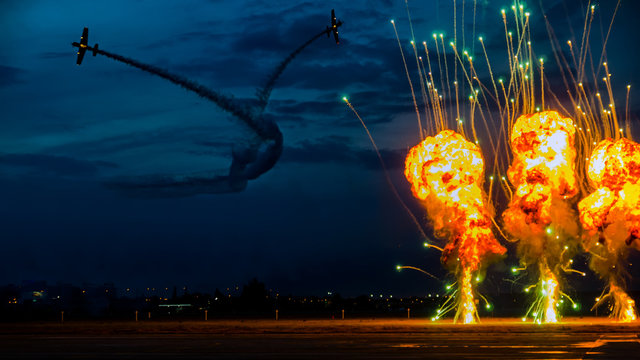 Bucharest, Romania - June 20, 2015 Yak 52 general aviation aerobatic airplane twilight pyrotechnic at airshow. Formation break simulation of world war 2 ground attack, fire, flames and explosion