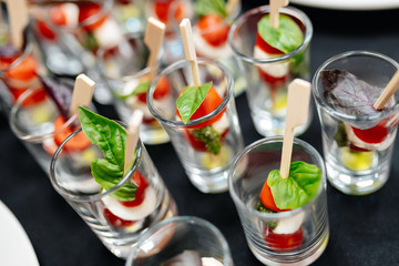 Fototapeta na wymiar Catering. Canapes with cherry tomatoes and basil leaf