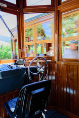 The driver's seat in the front rail car of an old, antique train - tram with a passing carriage blurred in the background