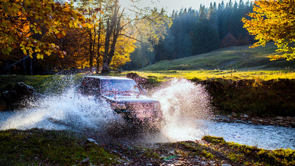 Extreme offroad car through river water generating splashes and sparks in the Carpahtians Mountains...