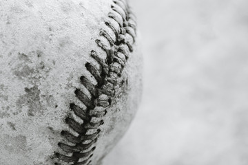 Macro view of old used baseball seams, grunge texture on ball in black and white with blurred background.