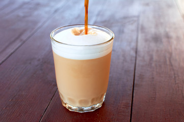 Morning Latte. Drink from milk and coffee. Strong espresso pours into a glass with milk and milk foam