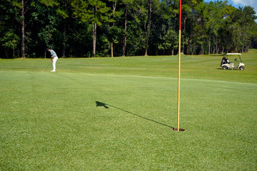 Obraz premium Golfer playing golf on the green grass with cart in the beautiful golf course at the sunshine.
