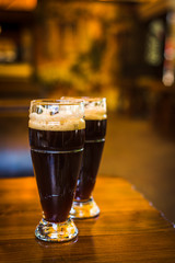 Glass with dark types of craft beer on a wooden bar. Glasses of different types of draft beer in a pub