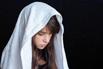 Obraz premium Close-up of a woman's face in a white scarf on a dark blue background, embarrassment, sadness, sadness