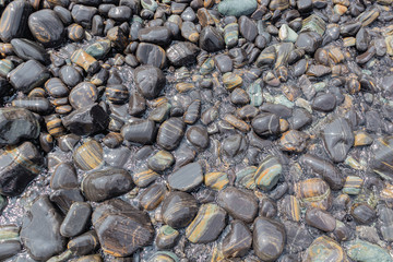 Beautiful wet black pebble stone beach shiny and smooth natural in tropical sea on coastline