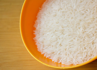 Jasmine rice seeds,Thai rice in a orange bowl on the wooden background.