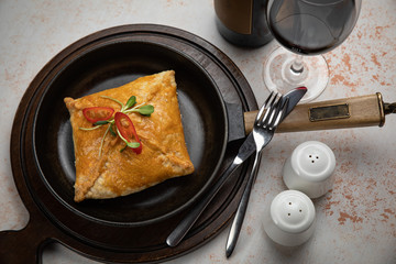 close-up of deep fried turnovers with a filling of minced beef and onion in a black ceramic pan on a white table