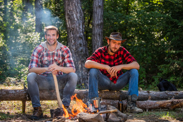 Discover life. Adventure concept. hike and people. two men relax at fire. hiking and camping. male friendship. man drink beer at bonfire. ranger at outdoor activities. spend picnic weekend in nature