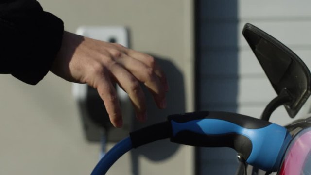 Charging electric vehicle with wallbox in background