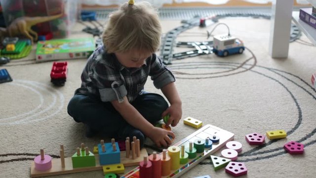 Little blonde toddler child,  boy playing with wooden toys developing and learning activities