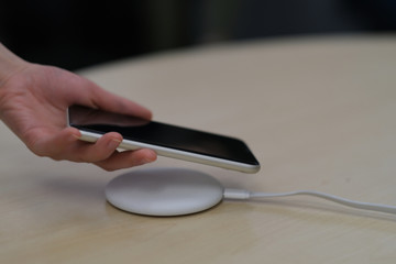 close up one hand putting smartphone on wireless charger. blur background