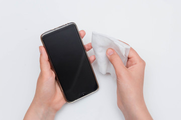 First-person view, hands wipe the smartphone with a wet wipe, isolated on a white background. The concept of the need for regular disinfection of gadgets.