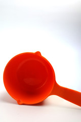 An orange measuring cup on a white background