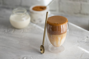 Creamy whipped Dalgona Coffee on white concrete background.