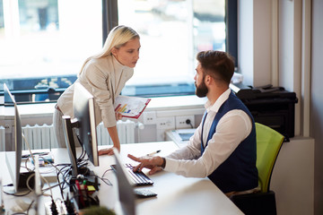 Businesswoman confronting a coworker. Businessman explaining mistakes on a computer.