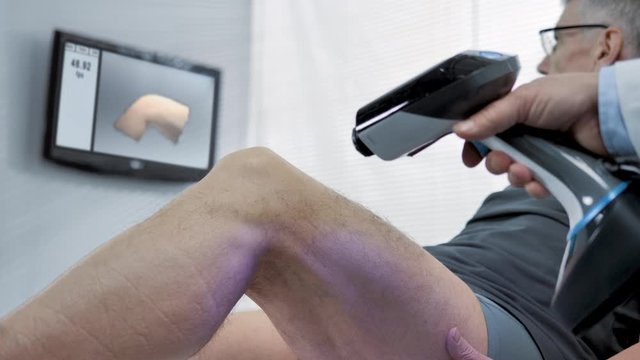 medical technology hand 3d scanner doctor scanning patient knee to acquire data to print a prosthesis