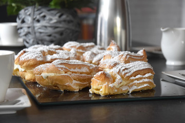 Eclairs mit SchlagsahneFüllung und Puderzucker auf einen Kaffee Tisch zu Hause