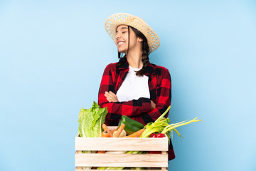 Young farmer Woman holding fresh vegetables in a wooden basket happy and smiling