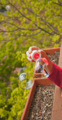 child's hand making soap bubbles, blurred background and vertical format
