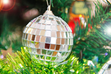 a shiny new year's ball on the branches of a green Christmas tree