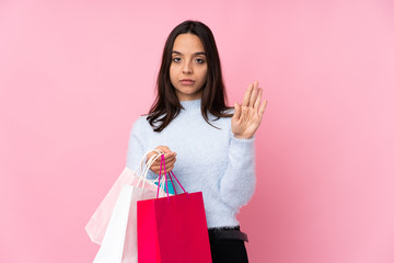 Fototapeta na wymiar Young woman with shopping bag over isolated pink background making stop gesture